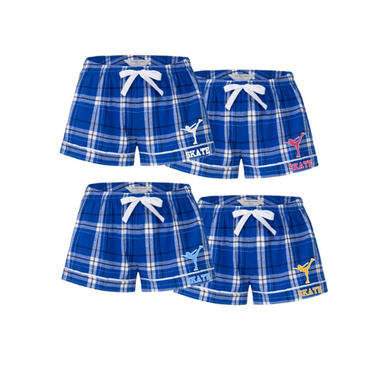 Four pairs of blue plaid shorts arranged in a 2x2 grid on a white background. Each pair has a white drawstring waist and a different colored logo on the left leg: white, red, light blue, and yellow.