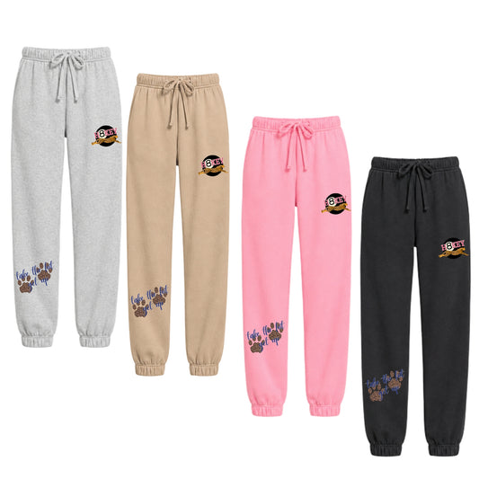 Jogger sweatpants in light gray, beige, pink, and black, each featuring Hockey Cheetah design on the upper thigh and a paw print graphic 'Take the hit, get up" tagline.